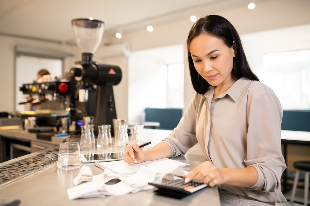 Restaurant manager making calculations for restaurant accounting