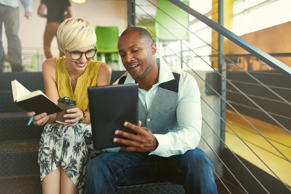 Two creative millenial small business owners working on social media strategy using a digital tablet while sitting in staircase-Nov-29-2023-03-15-14-6107-PM