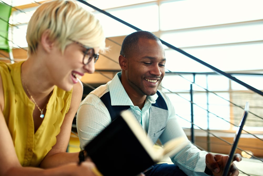 Two creative millenial small business owners working on social media strategy using a digital tablet while sitting in staircase-Oct-11-2023-12-05-18-7254-PM