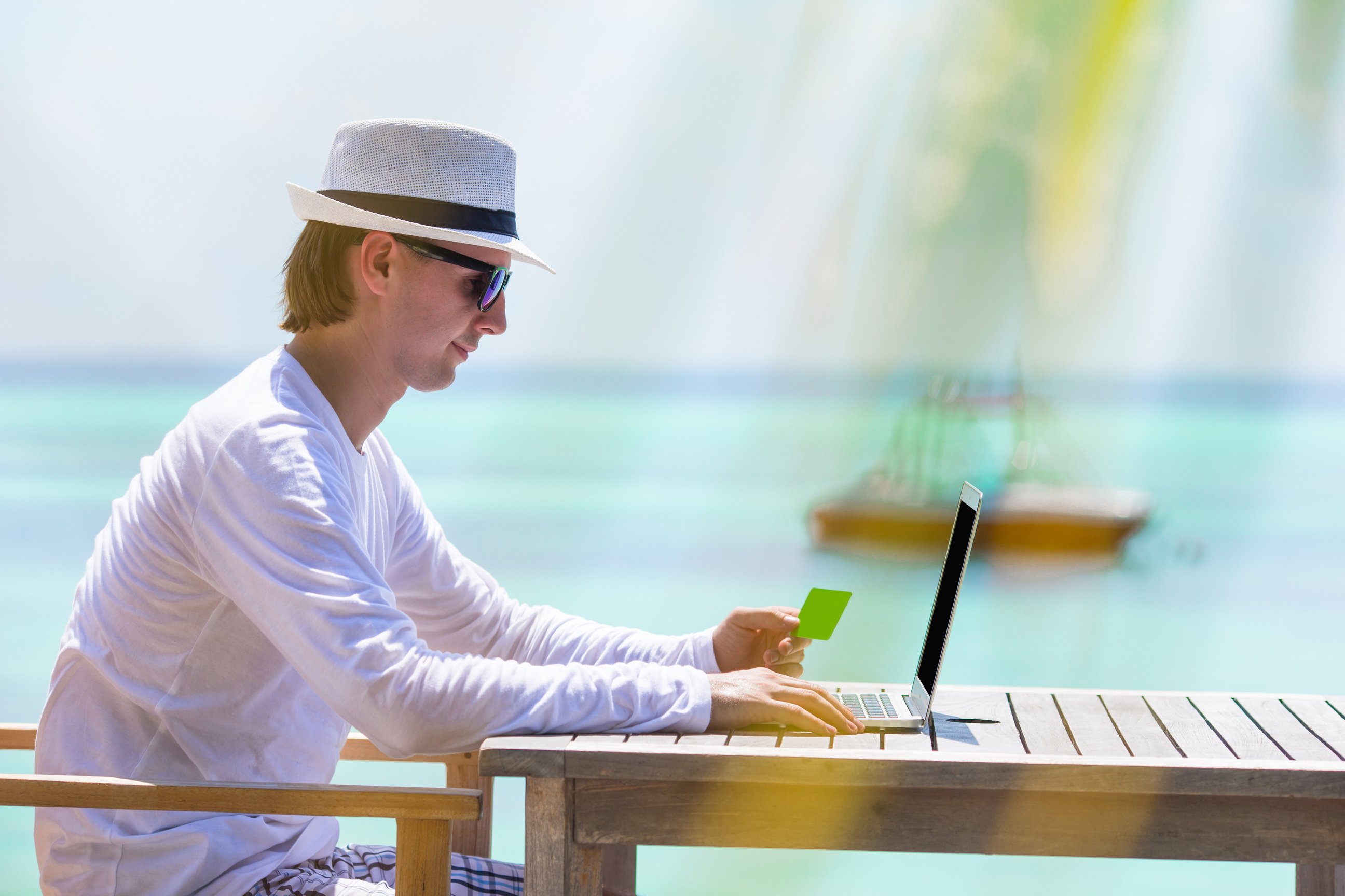 Hombre joven con tableta en una playa tropical que simboliza una workation