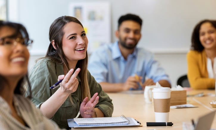 Empleados colaborando en una reunión para compartir ideas dentro de un programa de gestión del conocimiento.