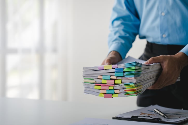 Hombre de negocios con una pila de documentos en la mano que simboliza el equilibrio de la carga de trabajo