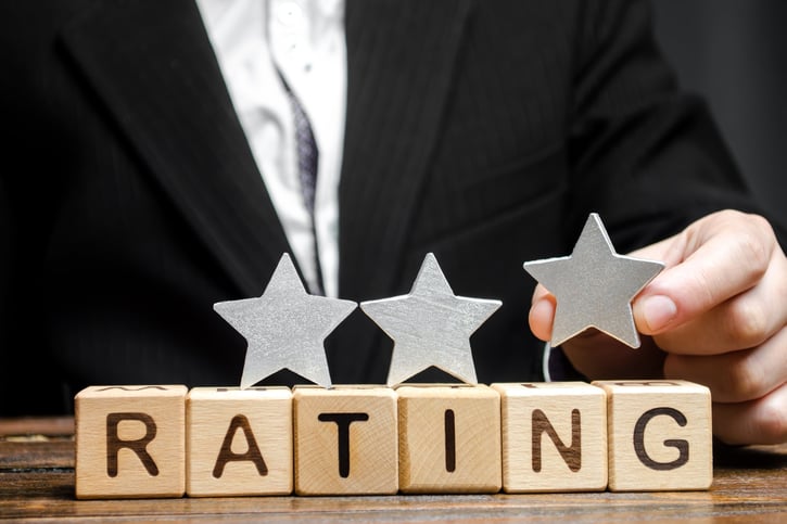 businessman putting star on wooden blocks that spell rating symbolising employee ratings
