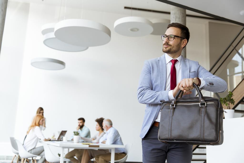 handsome businessman leaving office with bag in hand