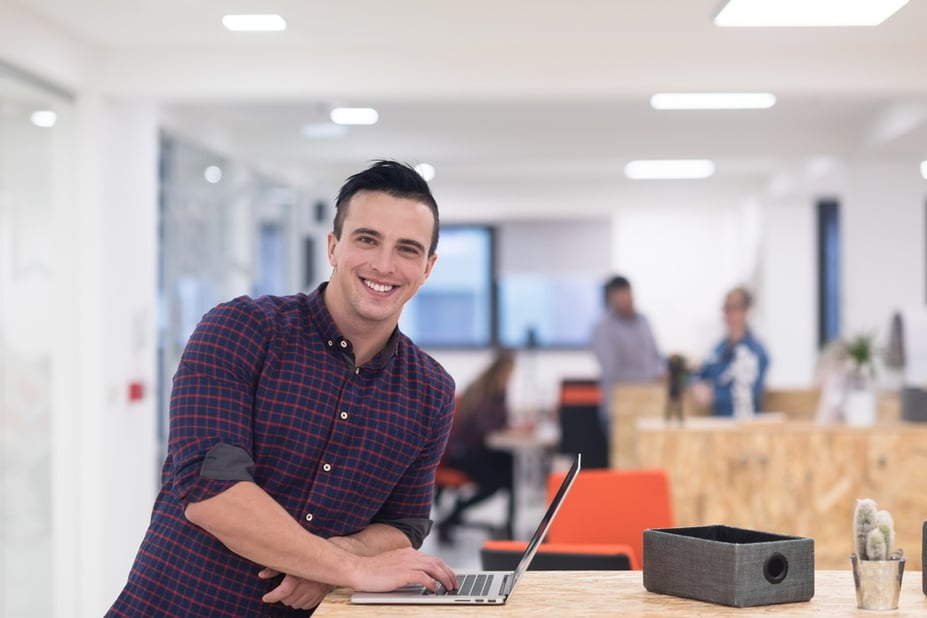 man die lacht met zijn laptop met urenregistratie systeem