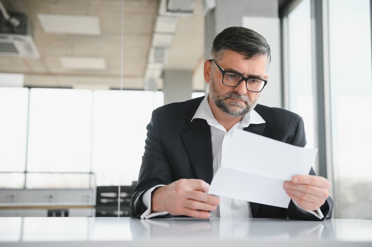 Un trabajador revisando un documento de amonestación laboral con expresión seria.