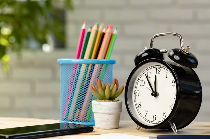 work desk with clock smartphone and pencils